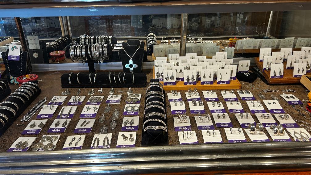 Display case featuring Silver Assets jewelry—silver bracelets, necklaces, rings, and earrings in classic Mesilla style.